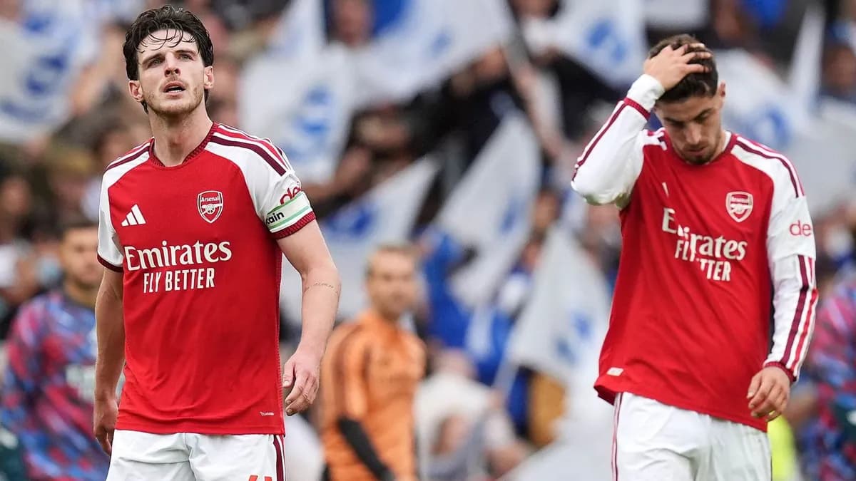 Arsenal captain Declan Rice and a dejected teammate walk off at the Amex Stadium as Brighton fans wave flags after the 3-0 defeat