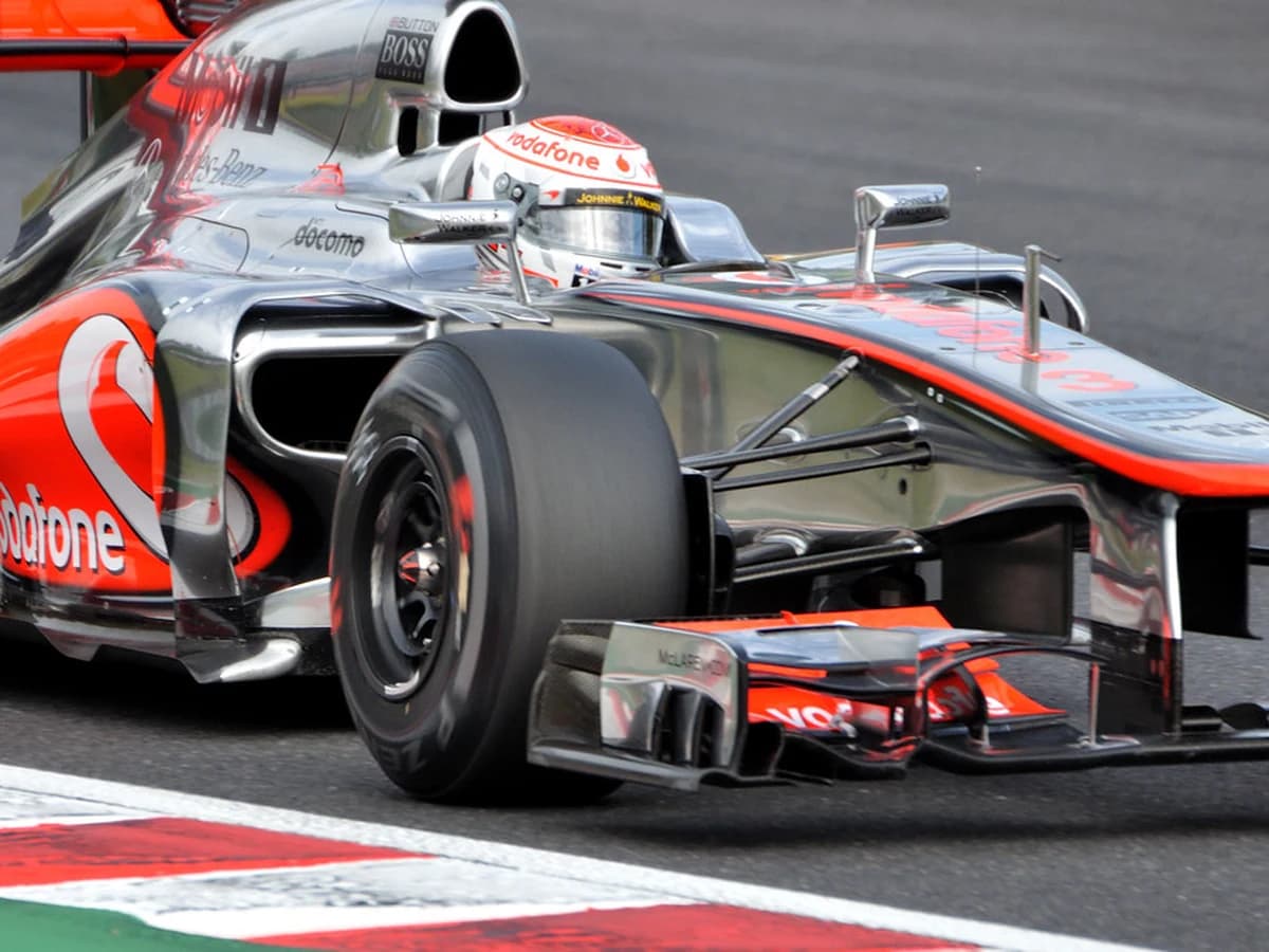 Young F1 driver in helmet giving a thumbs up on the grid