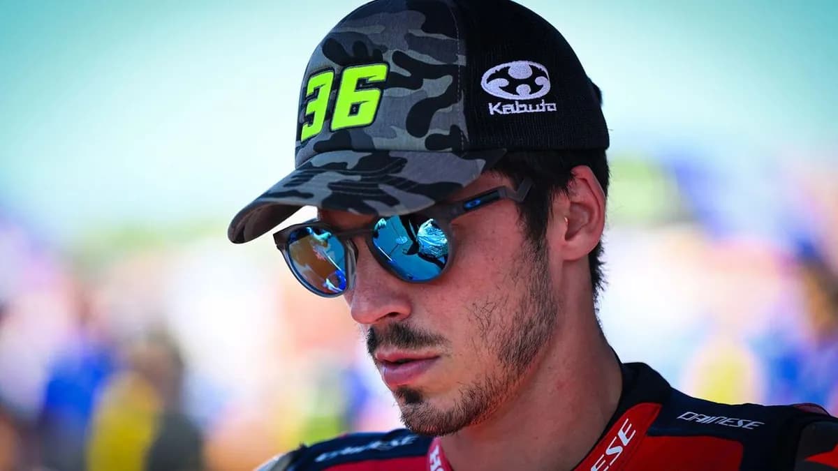 Close-up of Joan Mir wearing a camouflage number 36 cap and reflective sunglasses, looking down with a serious expression