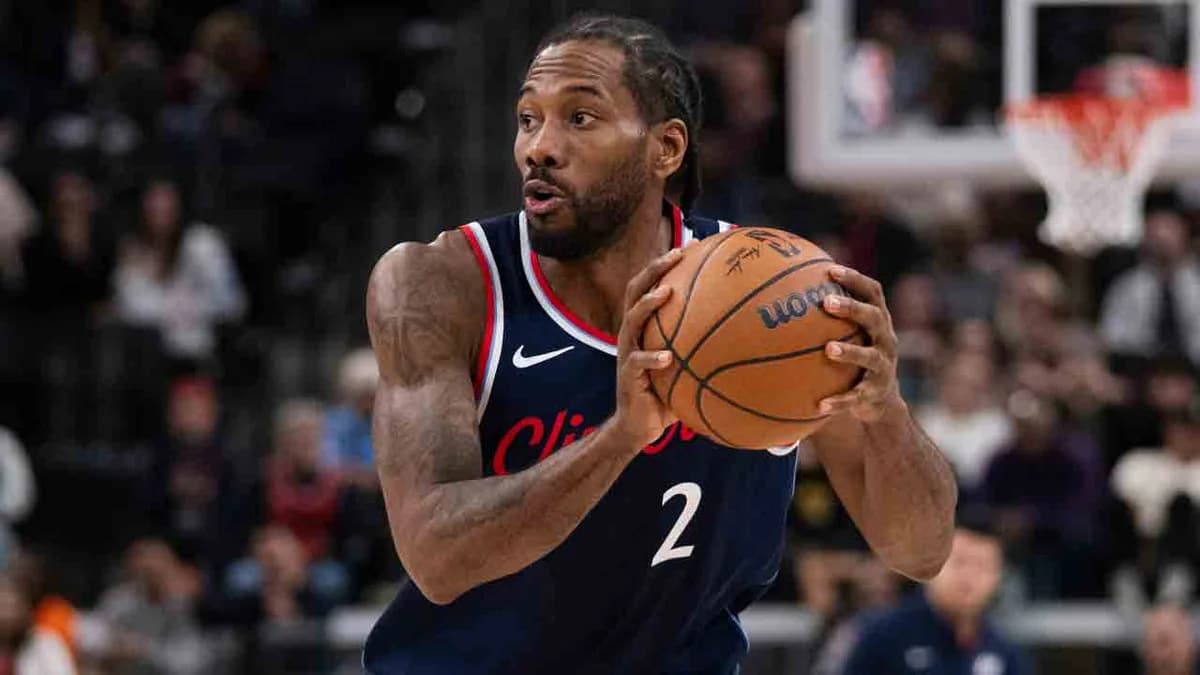 Kawhi Leonard holds a basketball while wearing a Los Angeles Clippers jersey
