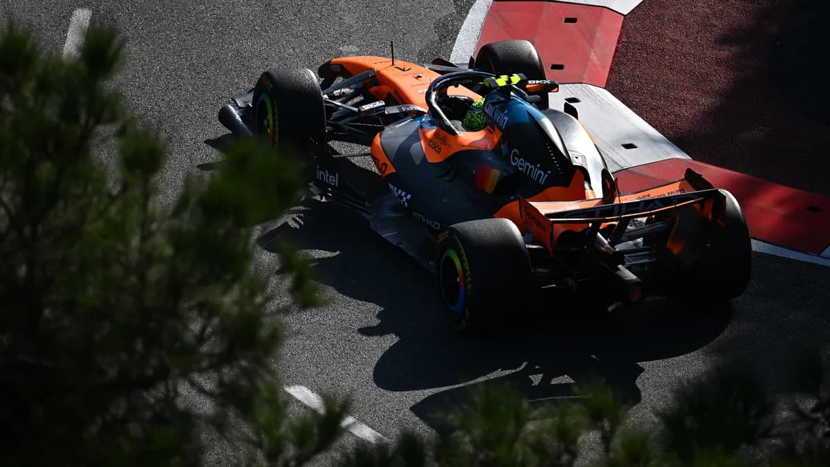 Lando Norris drives his papaya and black McLaren through a corner beside red and white kerbs at the Baku City Circuit