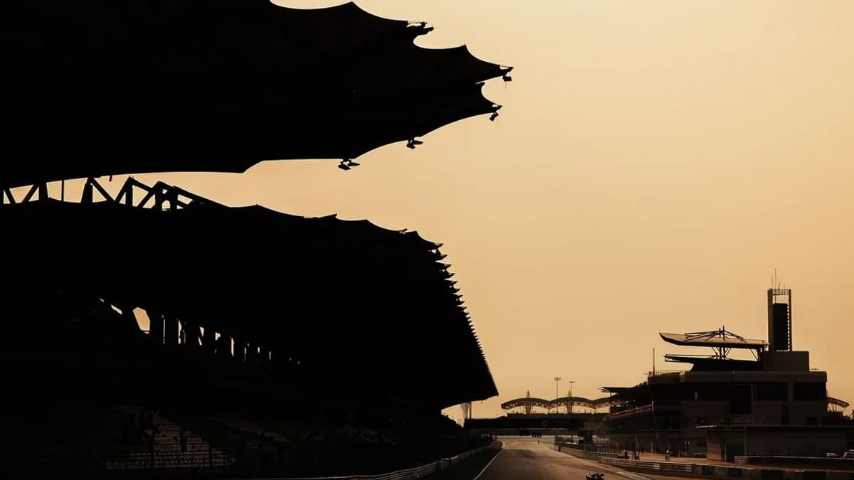 Sepang grandstand roof and circuit structures are silhouetted against a sunset