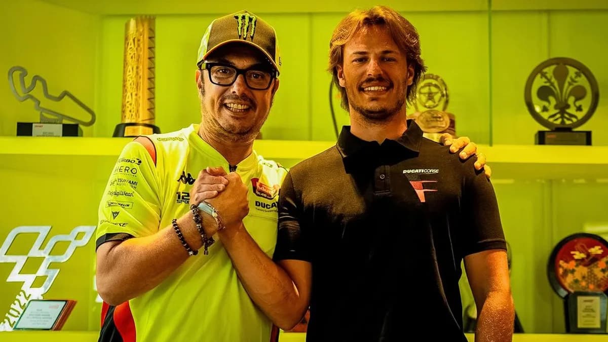 Nicolo Bulega shakes hands with Valentino Rossi in the VR46 signing photograph