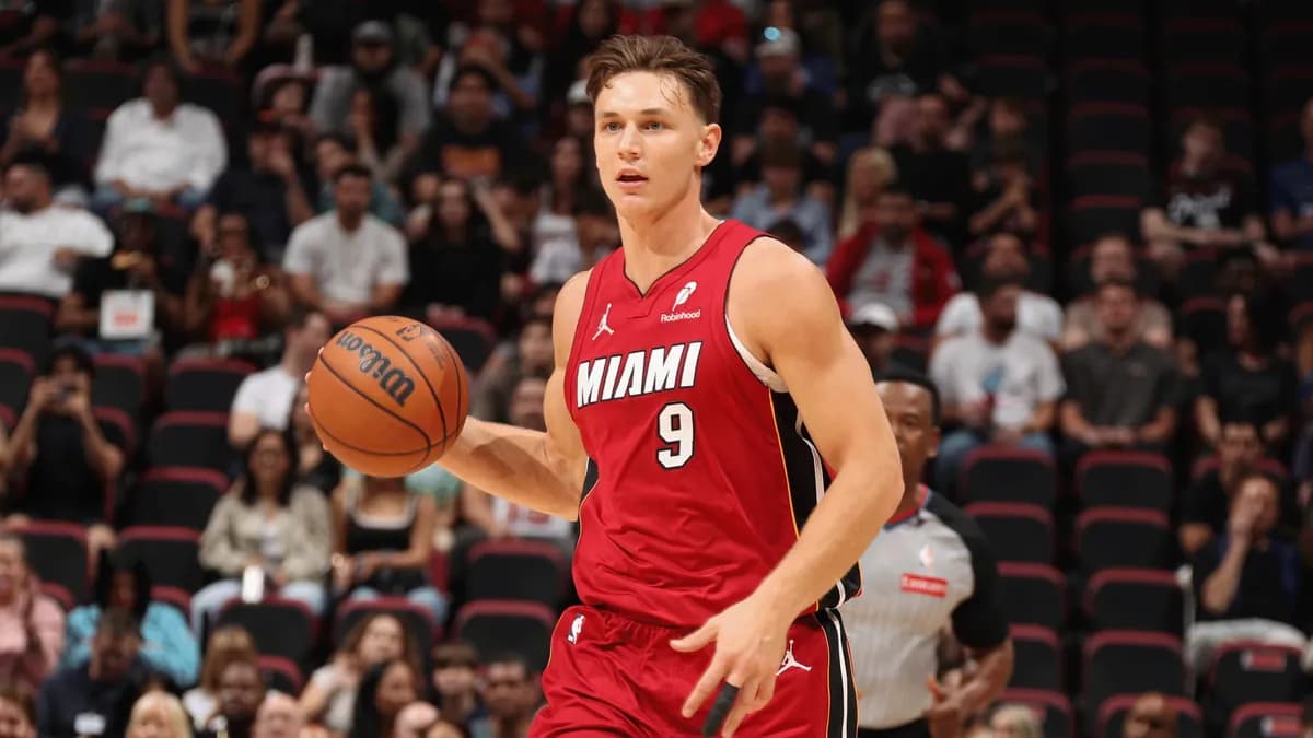 Pelle Larsson dribbles the ball up court in a red Miami Heat number 9 jersey in front of fans