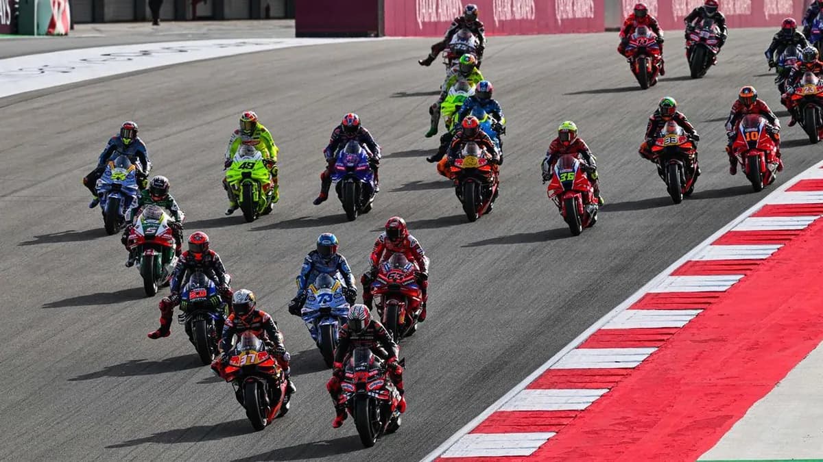 A full MotoGP field funnels into the first corner at the start of a race, led by Pedro Acosta’s number 37 KTM and an Aprilia