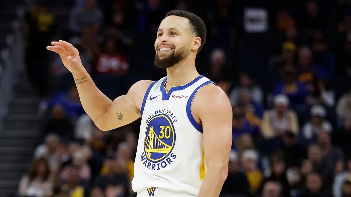 Stephen Curry smiles and gestures on court in a white Golden State Warriors number 30 jersey
