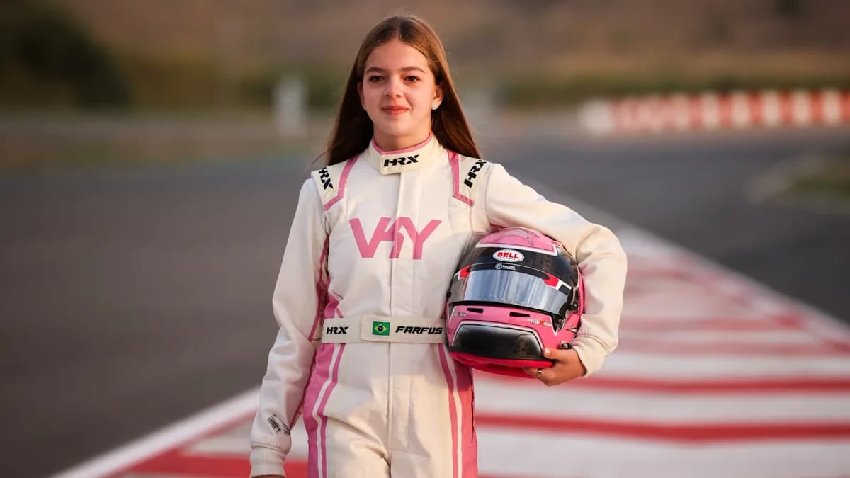 Victoria Farfus stands trackside in a white and pink racing suit holding her helmet